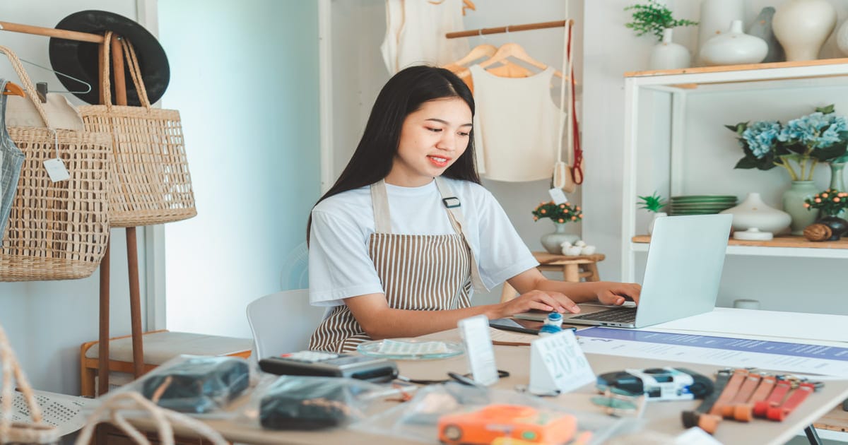 ノートパソコンを使って作業をするエプロン姿の女性