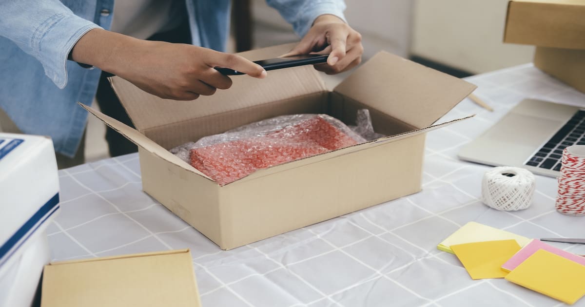 梱包された商品の写真をスマホで撮る人