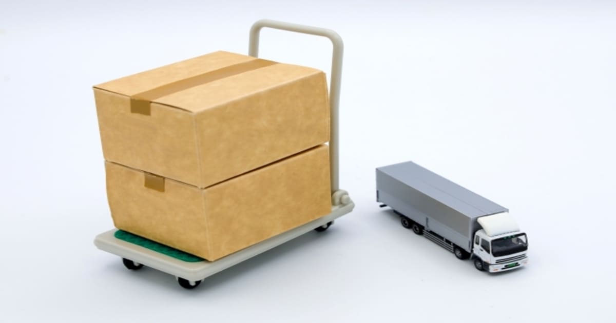 段ボール箱が積まれた台車とトラック