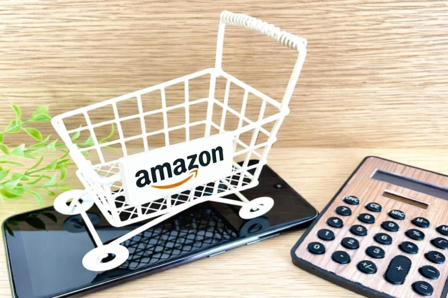 スマートフォンの上に乗ったショッピングカートと電卓